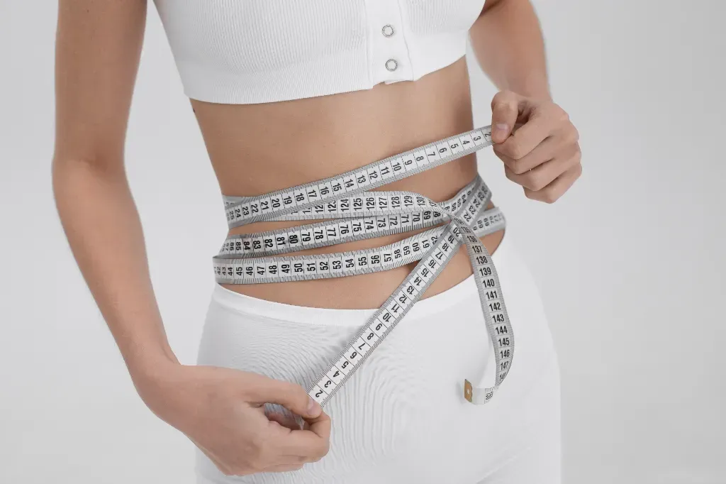 kobieta mierząca swoje ciało metrem